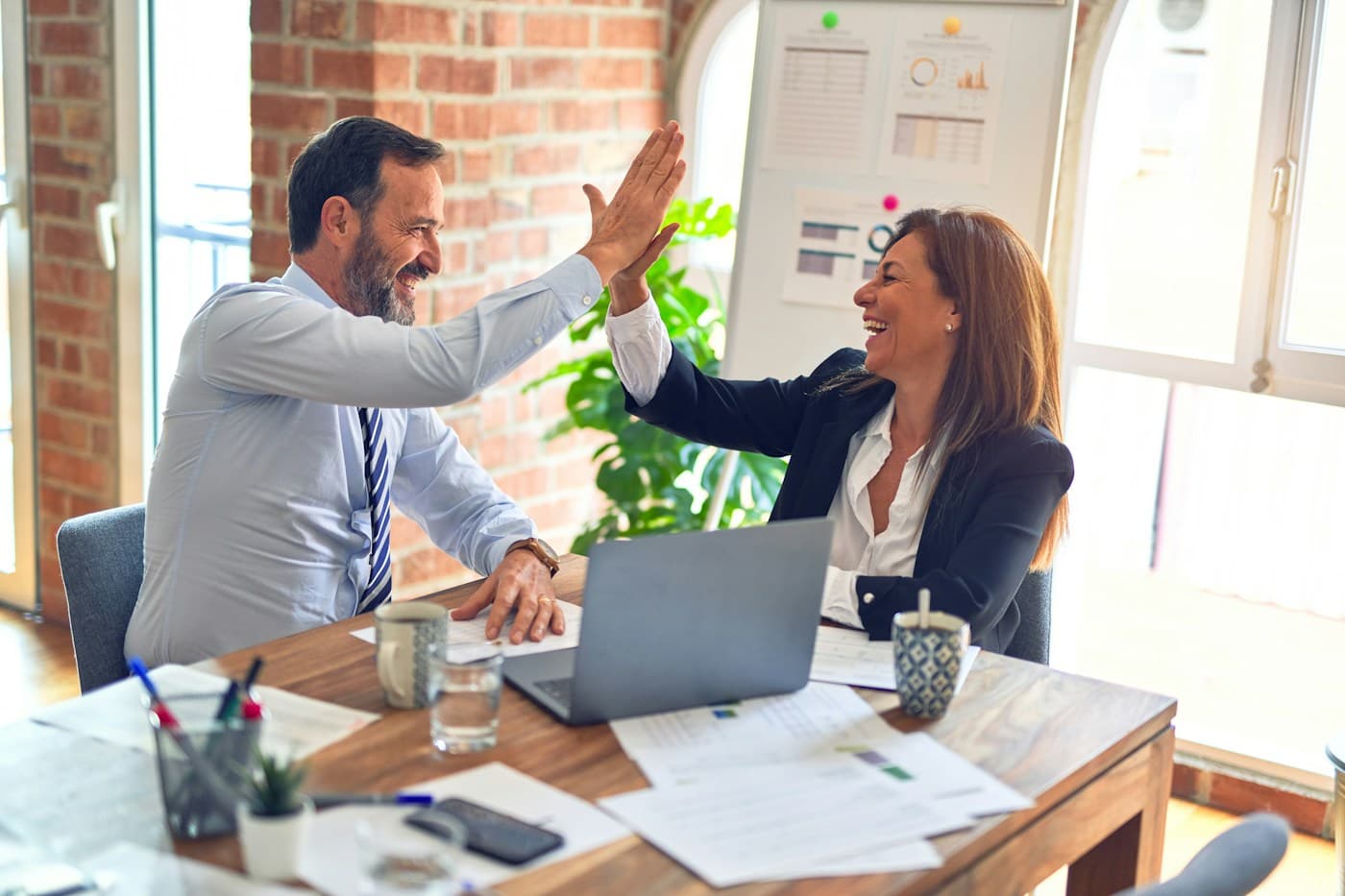 Two colleagues celebrating progress during a team conversation